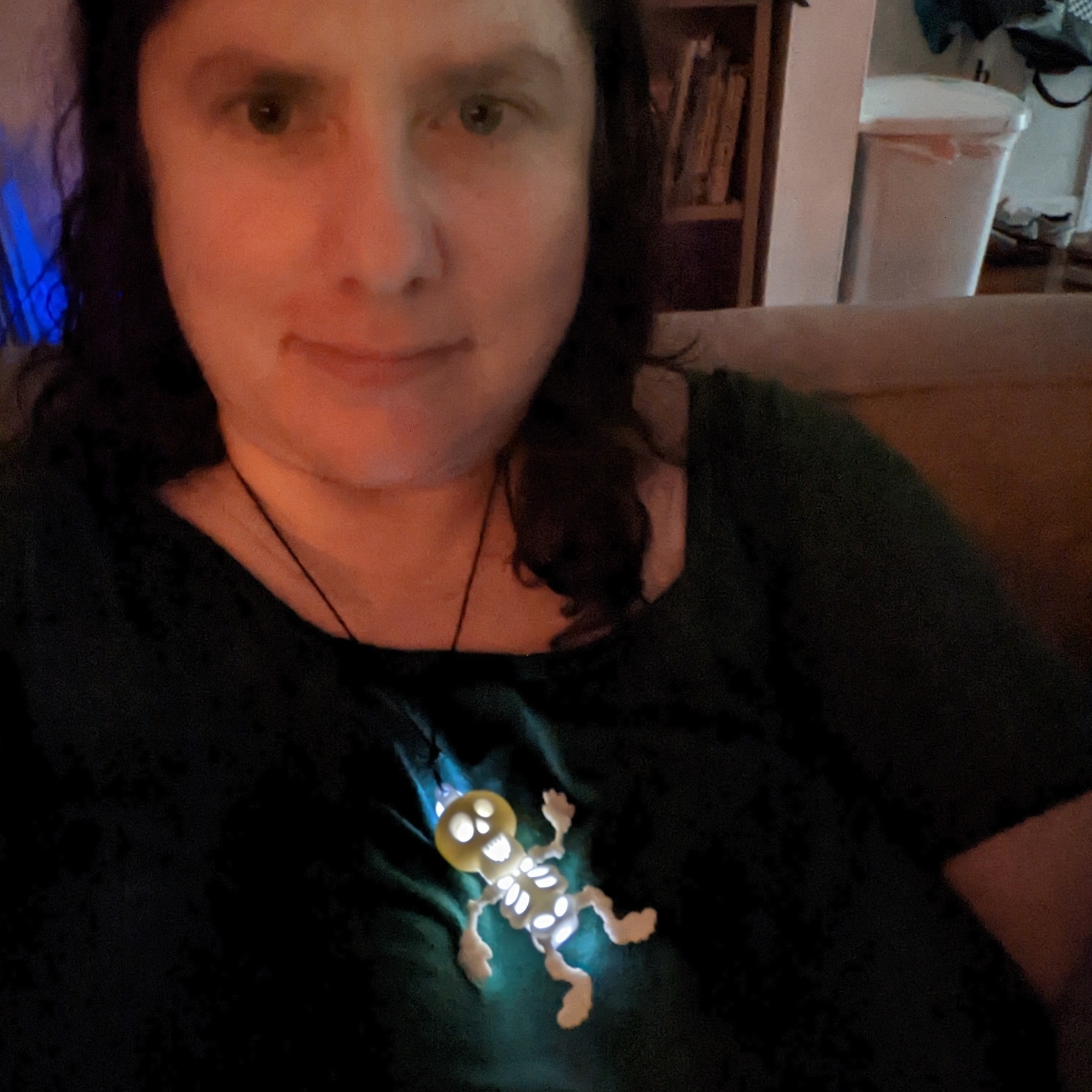 A white woman wears a skeleton-shaped necklace with a white glow stick inside it.